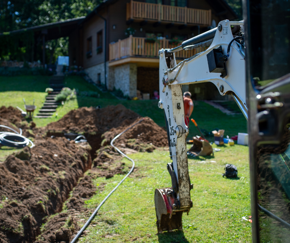 A construction site with an excavator in action. Overlay text reads: "Potreban rukovalac građevinskim mašinama, mesto rada: Ruma, pošaljite CV." The setting is outdoors with a house in the background.