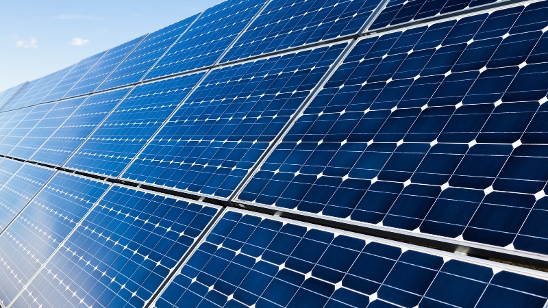 Krupni plan niza plavih solarnih fotonaponskih panela pod sunčevim svetlom.